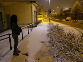 雪の降った歩道に立つ女性