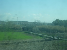 緑の畑の奥に見える水道橋