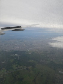 空を飛ぶ飛行機の翼と下に広がる大地と海