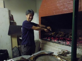 炭火の釜で肉を焼く男性