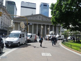 神殿風の建築物とその前に停まる車と人