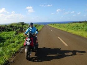 草原の中の一本道を走るバイク