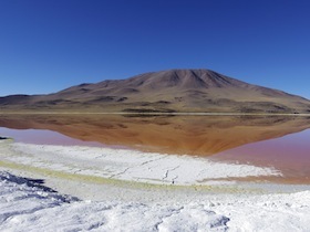 白い大地と水面に反転する赤い山と青い空