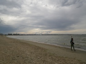 曇り空の浜辺に立つ人