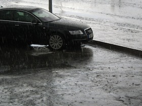 土砂降りの雨の中停っている黒い車