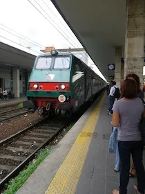 緑と赤の列車が入線してくる駅のホーム