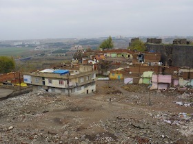 ゴミ捨て場のような空き地とその側に建つ住居