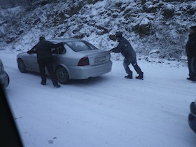 雪道でスリップした車を押す人たち