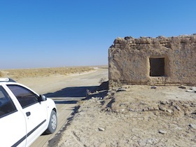 砂漠にある土壁の小屋と白い車