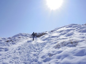 太陽が照りつける雪山を登る人