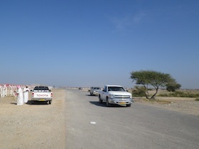 砂漠の上の道路を走る車と路肩に停まる車