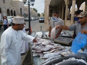 陳列している魚を買うアラブの装束の男性