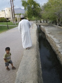 道路の脇の水路と白い衣装の男性と子供