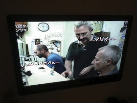 男性三人が映るテレビのモニター