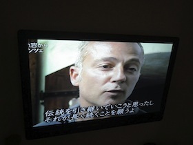 男性と日本語字幕が映るテレビモニター