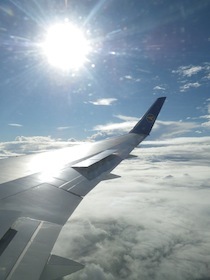 雲の上の飛行機の羽と太陽