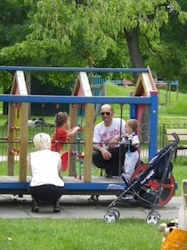 公園の遊具で遊ぶ子供を見守る大人たち