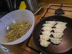 フライパンの上の餃子とボウルに入った餃子の具