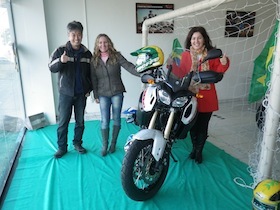 サッカーゴールのディスプレイの前にあるバイクと女性二人と男性一人