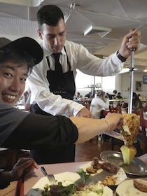 焼きパイナップルを切る男性とそれを受け取る男性