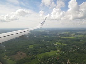 緑の大地の上を飛ぶ飛行機の羽と空