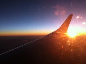 夕焼けの空を飛ぶ飛行機の翼