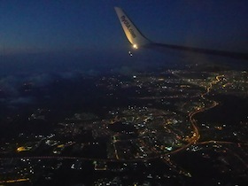 夜景の上を飛ぶ飛行機の羽