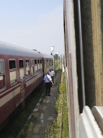 赤い列車の横を歩く二人の車掌